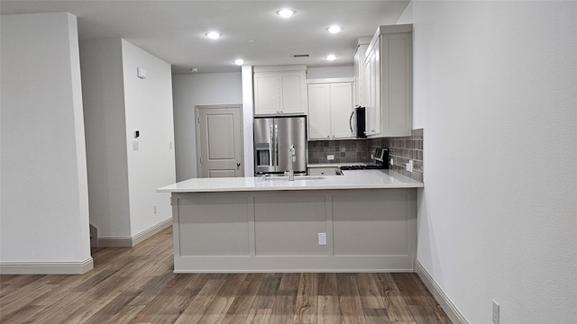 kitchen featuring sink, white cabinetry, tasteful backsplash, kitchen peninsula, and stainless steel appliances