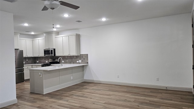 kitchen featuring backsplash, stainless steel appliances, light hardwood / wood-style floors, white cabinets, and kitchen peninsula