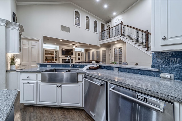 kitchen featuring sink, stainless steel dishwasher, white cabinets, and a towering ceiling