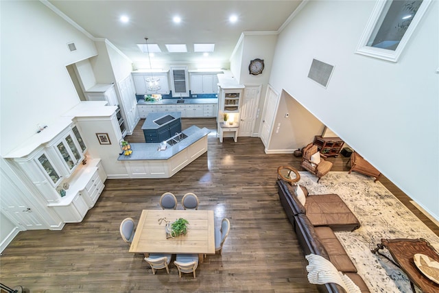 living room featuring a high ceiling, crown molding, dark hardwood / wood-style floors, and a skylight