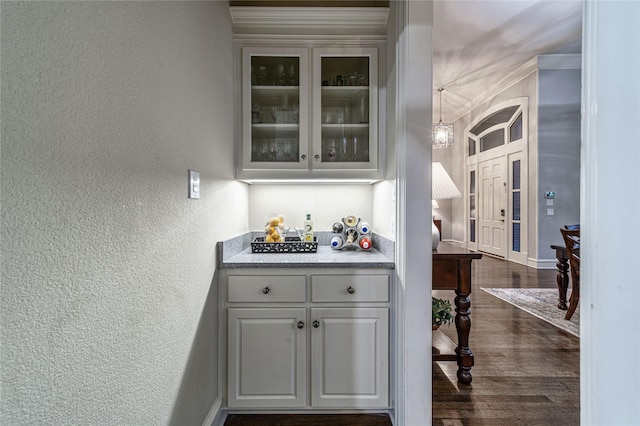 bar with white cabinetry, ornamental molding, and dark wood-type flooring