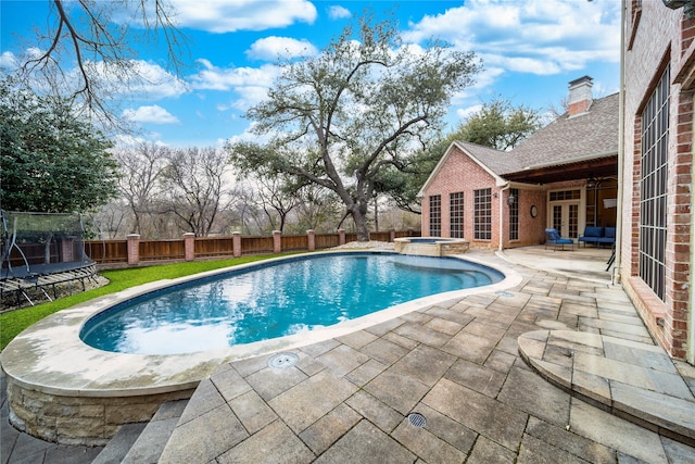 view of pool featuring an in ground hot tub, a trampoline, and a patio area