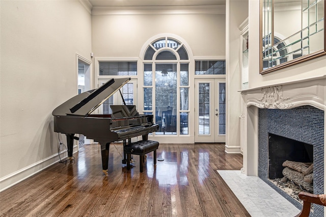 living area featuring crown molding, hardwood / wood-style flooring, a tile fireplace, and a towering ceiling