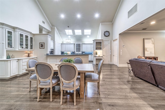 dining room with hardwood / wood-style flooring, ornamental molding, high vaulted ceiling, and a skylight