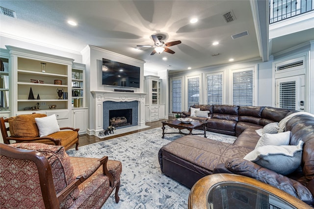 living room with hardwood / wood-style flooring, a high end fireplace, ornamental molding, and ceiling fan