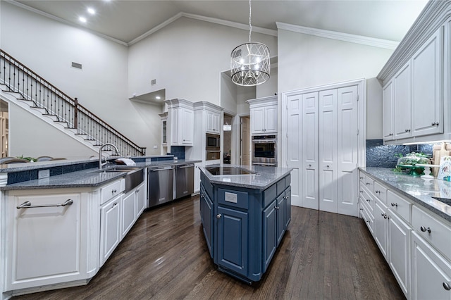 kitchen with white cabinetry, an island with sink, appliances with stainless steel finishes, and blue cabinets