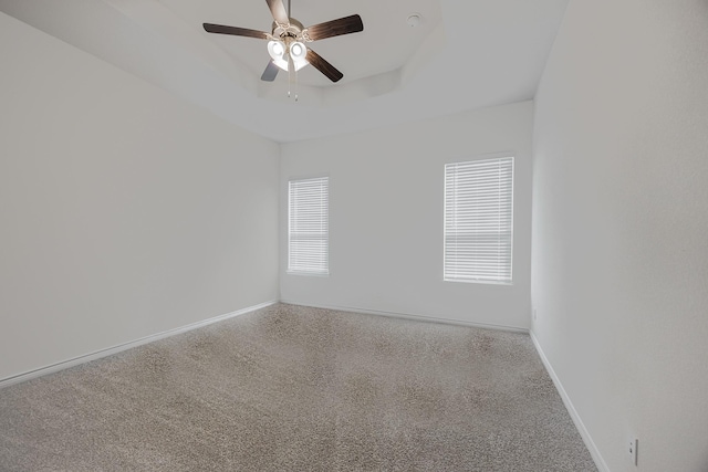 carpeted spare room with ceiling fan and a tray ceiling