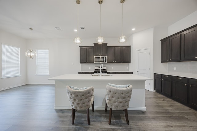 kitchen with a center island with sink, pendant lighting, sink, and dark brown cabinetry