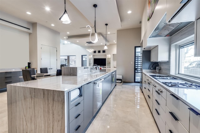 kitchen featuring gray cabinets, decorative light fixtures, tasteful backsplash, a large island, and light stone counters