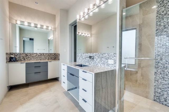 bathroom featuring a shower with door, vanity, and backsplash