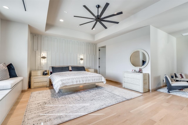 bedroom with a raised ceiling and light wood-type flooring