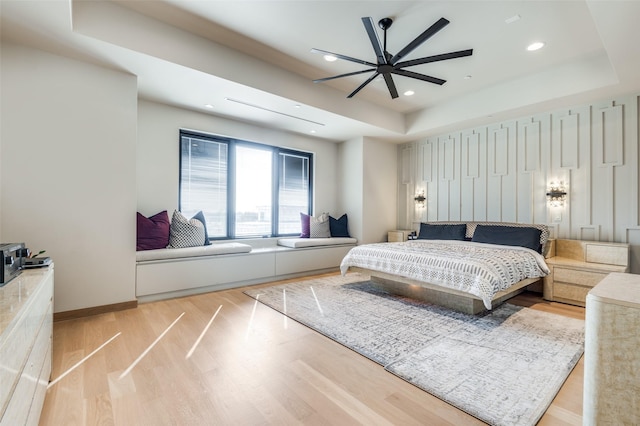 bedroom with a tray ceiling and light wood-type flooring