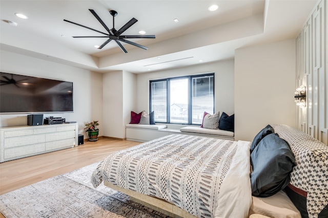 bedroom with a tray ceiling, ceiling fan, and light wood-type flooring