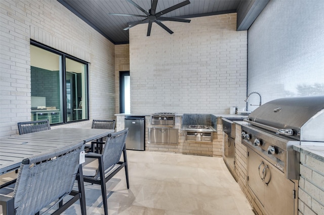 view of patio featuring exterior kitchen, area for grilling, ceiling fan, and a bar