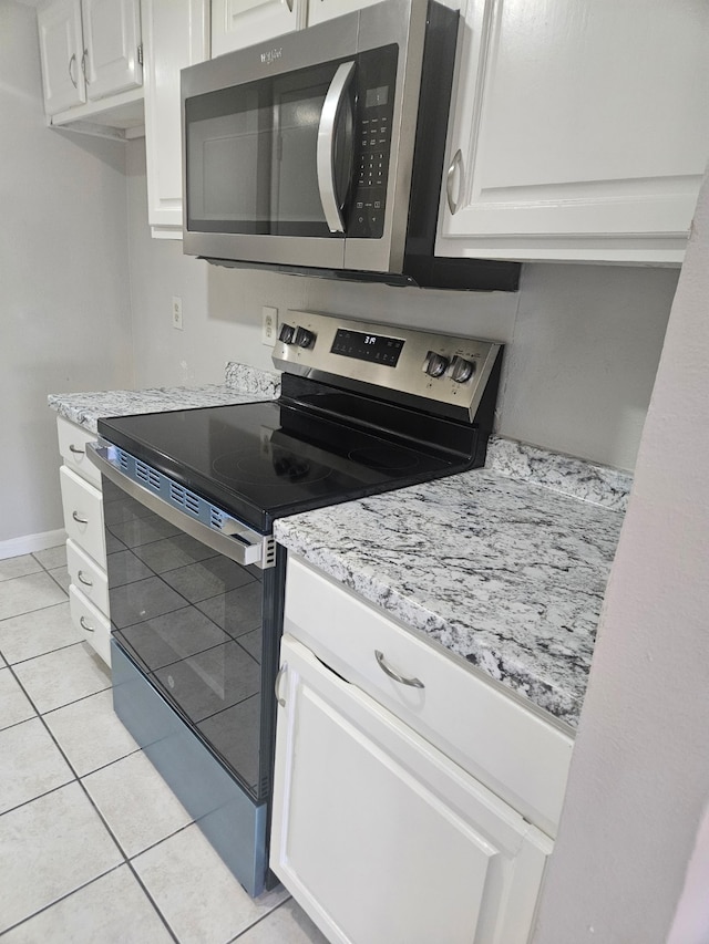 kitchen with light tile patterned flooring, stainless steel appliances, and white cabinets