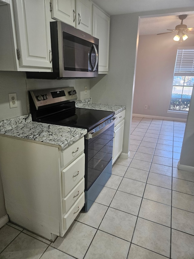 kitchen with electric range oven, light tile patterned floors, white cabinets, and ceiling fan