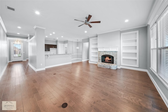 unfurnished living room with hardwood / wood-style flooring, plenty of natural light, ceiling fan, and built in shelves