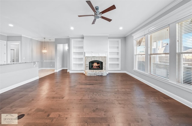 unfurnished living room featuring ornamental molding, a brick fireplace, dark wood-type flooring, and ceiling fan