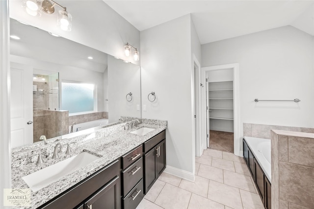 bathroom featuring vaulted ceiling, vanity, plus walk in shower, and tile patterned flooring