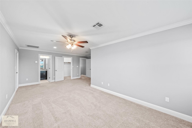 unfurnished bedroom featuring crown molding, ceiling fan, connected bathroom, a walk in closet, and light colored carpet