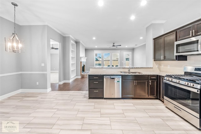 kitchen featuring sink, stainless steel appliances, dark brown cabinetry, light stone countertops, and ceiling fan with notable chandelier