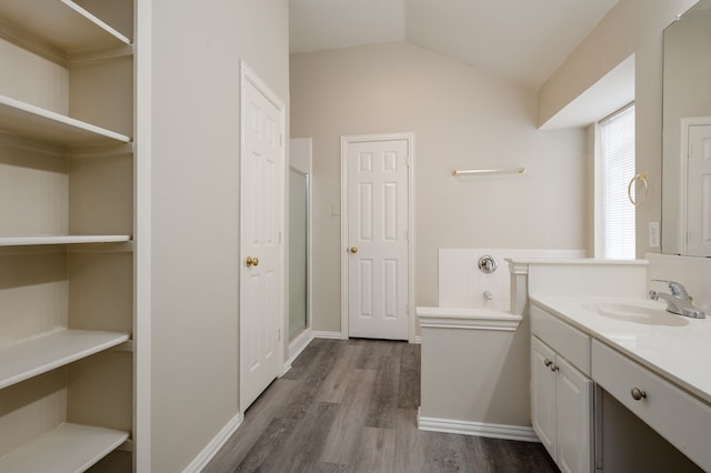 bathroom featuring hardwood / wood-style flooring, lofted ceiling, walk in shower, and vanity