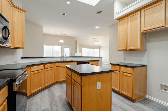 kitchen featuring sink, a center island, black appliances, decorative light fixtures, and kitchen peninsula