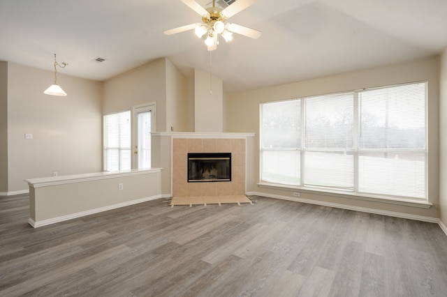 unfurnished living room featuring a tiled fireplace, wood-type flooring, vaulted ceiling, and ceiling fan