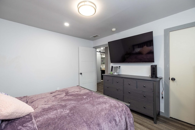 bedroom with dark hardwood / wood-style floors and a barn door