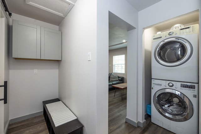 clothes washing area with dark wood-type flooring and stacked washer and dryer