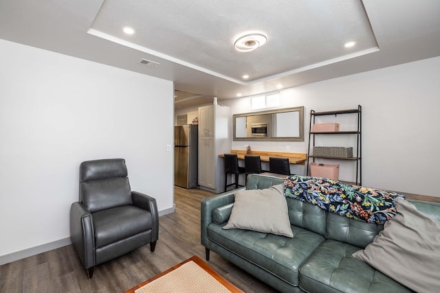 living room with wood-type flooring and a tray ceiling