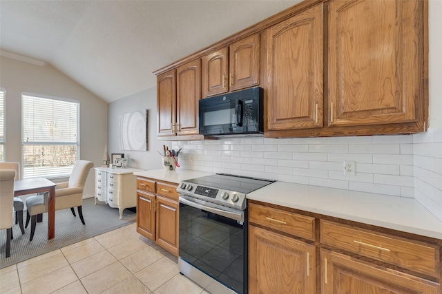 kitchen with vaulted ceiling, stainless steel electric range, black microwave, and brown cabinetry