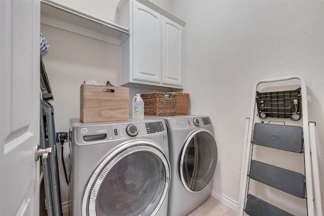 washroom with washing machine and dryer, cabinet space, and baseboards