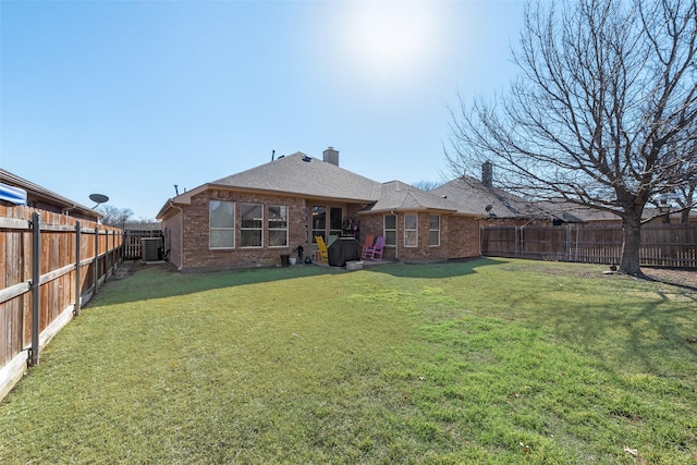 back of house with brick siding, a lawn, and a fenced backyard