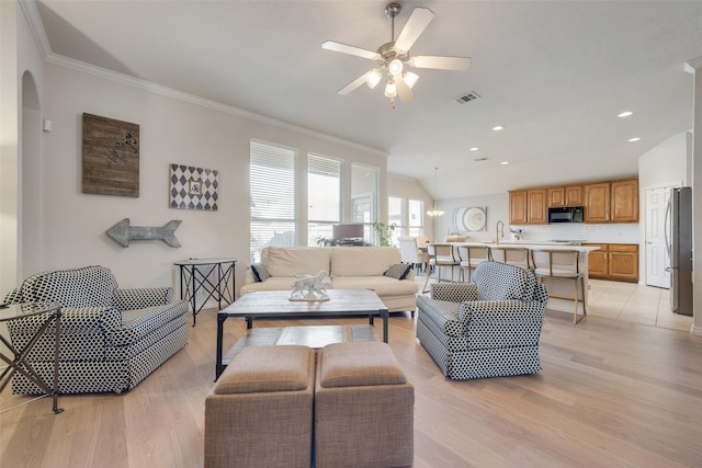 living room with lofted ceiling, light wood-type flooring, visible vents, and crown molding