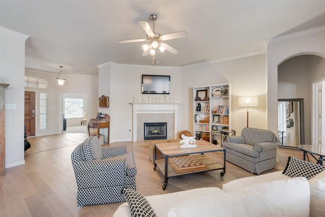 living room with light wood-style floors, ceiling fan, a premium fireplace, and ornamental molding