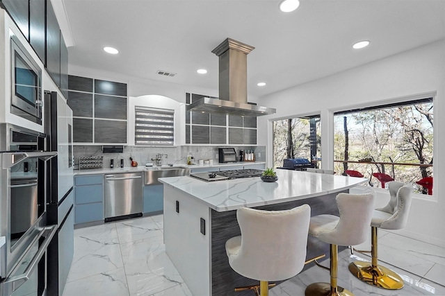 kitchen featuring sink, appliances with stainless steel finishes, a center island, tasteful backsplash, and island exhaust hood