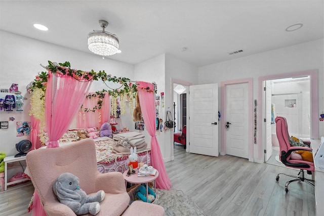 bedroom featuring an inviting chandelier and light hardwood / wood-style floors