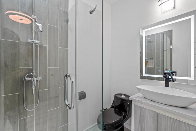 bathroom with vanity, toilet, and a shower with door