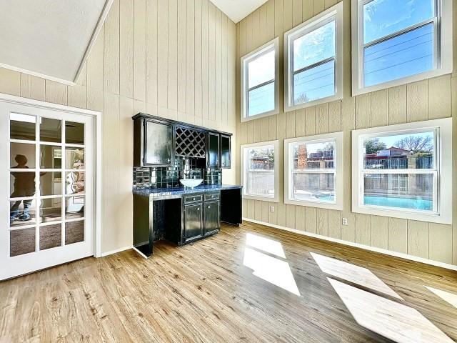 bar with high vaulted ceiling, wooden walls, and light hardwood / wood-style floors