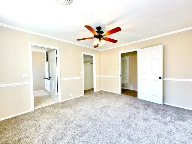 unfurnished bedroom featuring crown molding, a closet, connected bathroom, and light carpet