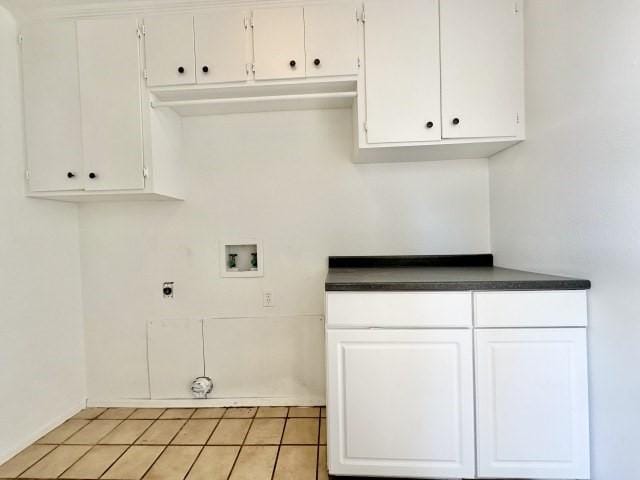 laundry room featuring electric dryer hookup, light tile patterned floors, hookup for a washing machine, and cabinets