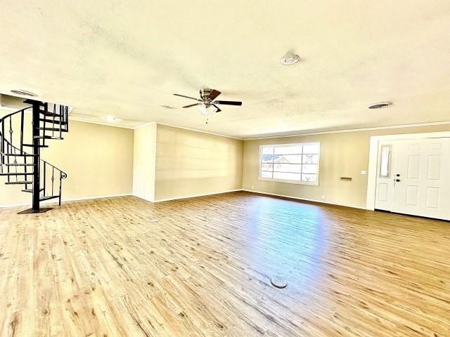 unfurnished living room with wood-type flooring, a textured ceiling, ceiling fan, and crown molding