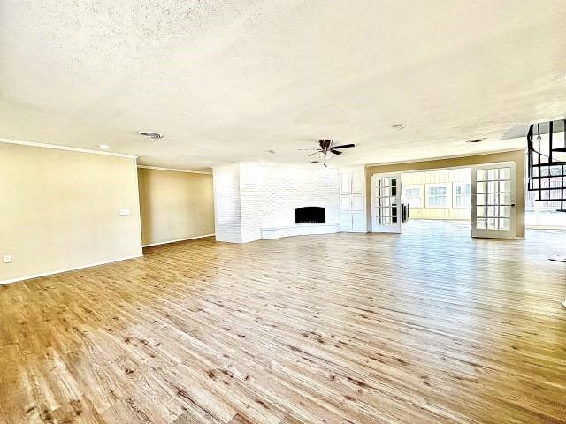 unfurnished living room with ceiling fan, ornamental molding, light hardwood / wood-style floors, and a textured ceiling