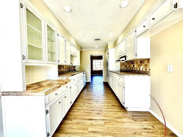 kitchen featuring white cabinetry, sink, dark stone counters, crown molding, and light hardwood / wood-style flooring