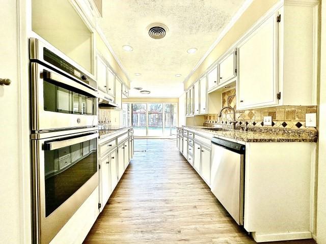 kitchen featuring light stone counters, stainless steel appliances, sink, and white cabinets