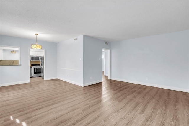 unfurnished living room featuring a textured ceiling and light wood-type flooring