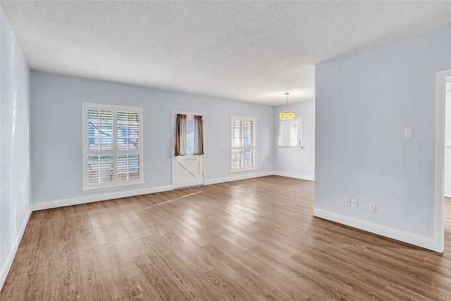 unfurnished living room featuring wood-type flooring, a wealth of natural light, and a textured ceiling