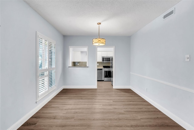 unfurnished dining area with hardwood / wood-style flooring and a textured ceiling