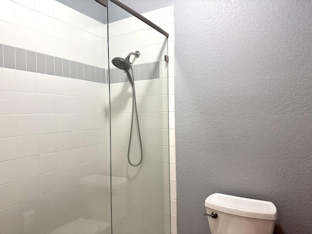 bathroom with tiled shower and toilet